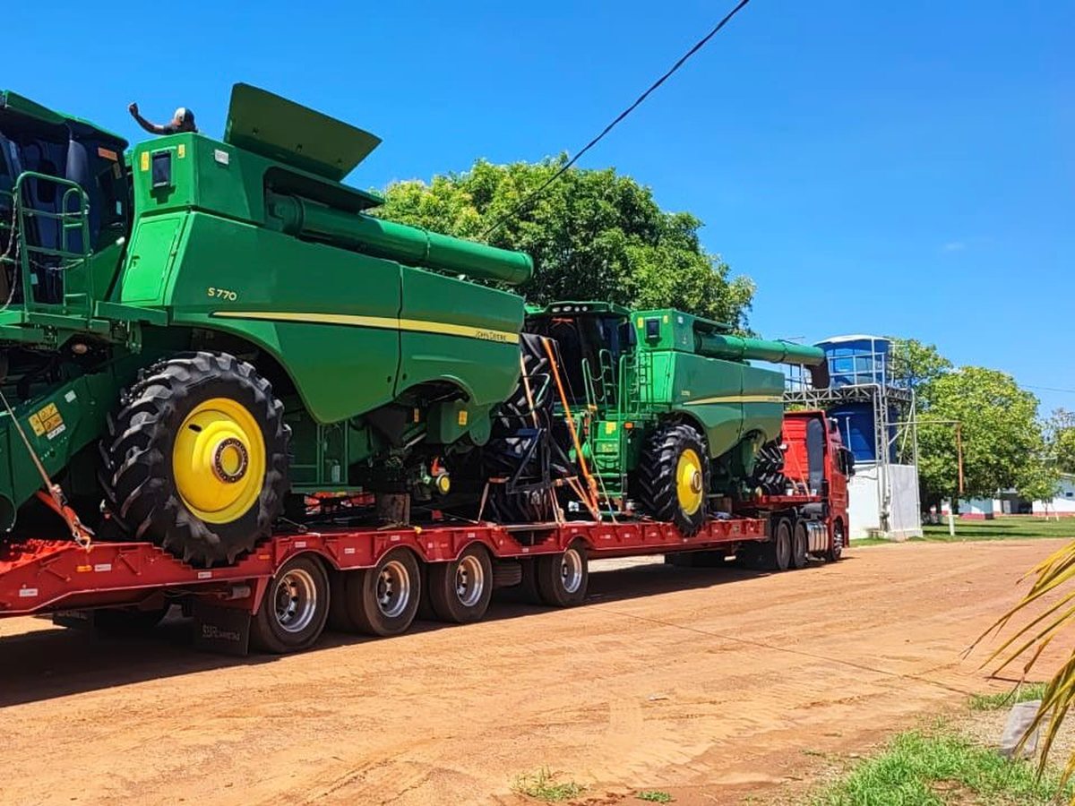 Duas colheitadeiras John Deere sobre prancha rebaixada no pátio do terminal
